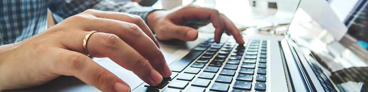 Hands typing on a computer laptop