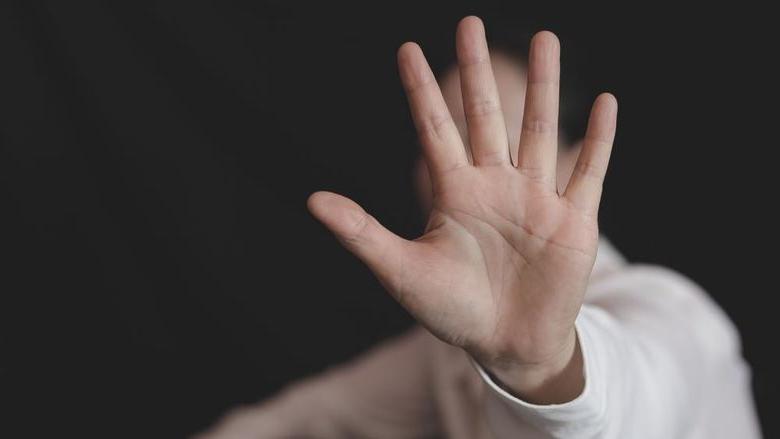 A photo of a woman holding her hand out to stop a sexual assault