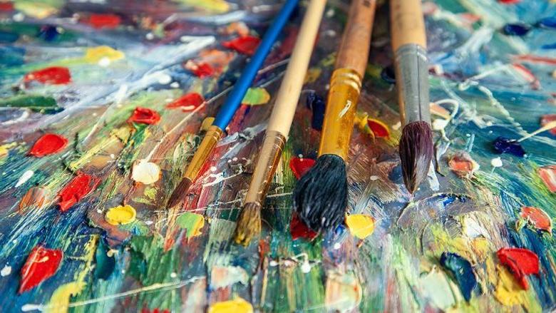 Several paint brushes laying on top of a piece of art 