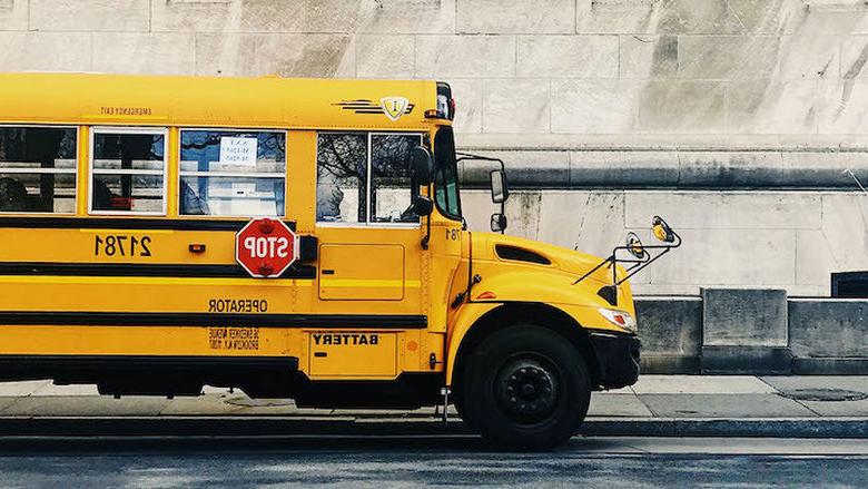 Yellow school bus outside of a school.